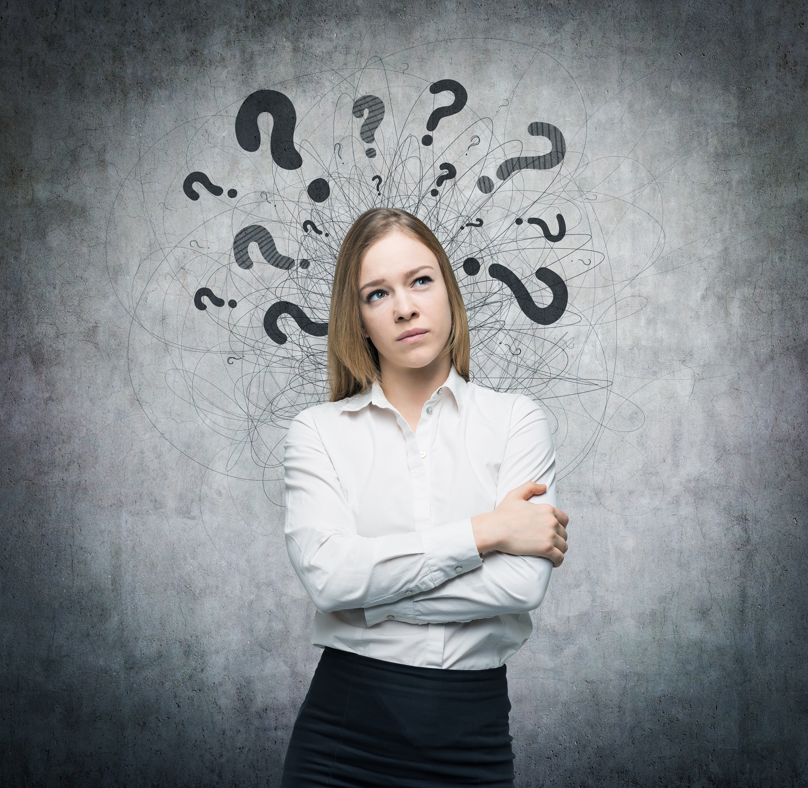 A person standing against a grey wall with their arms crossed looking puzzled. Lots of questions marks surround their head.