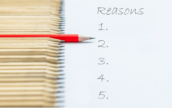 A line of sharpened wooden pencils, one red pencil stands out from the others in the line. The pencils are on top of a piece of paper that reads "Reasons" and an empty list from 1 to 5.