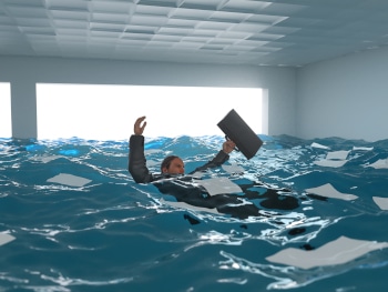 A business person floating in an office full of water.