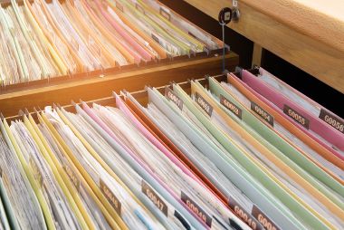 Financial documents in colorful folders are stored in filing cabinets.