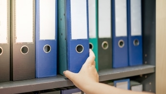 Female hand pick a binder of document on the row of file folders