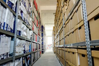 Stacks of files and paperwork placed in bookshelves with folders and documents in binders and cardboard box, archive, storage room.