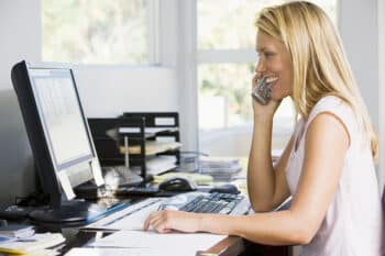 Woman sitting at her desk working in home office, on the phone. 