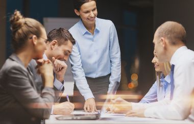 Smiling woman talking to business team in conference room